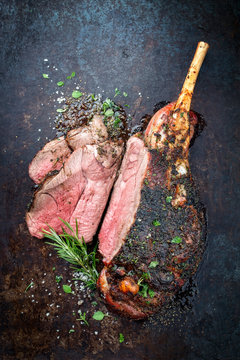 Traditional barbecue leg of lamb sliced with spice and herb as top view on a metal sheet
