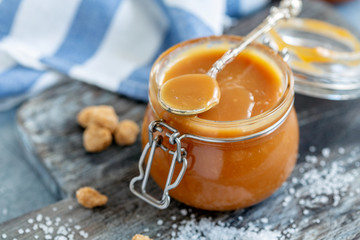 Spoon in a glass jar with salted caramel close-up.