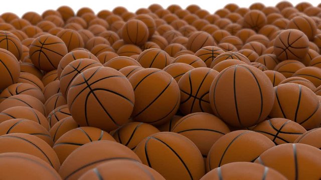 Animated zooming out from close up of pile of basketballs laying on white background or base.