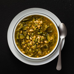 gluten free green minestrone with cannellini beans. on the table with spices and arugula pesto. Traditional Italian Tuscan soup. healthy food for the whole family on black background