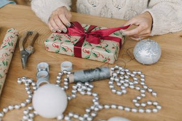 Fototapeta na wymiar woman decorating christmas gift on wooden table