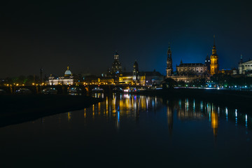 Naklejka na ściany i meble View of the old town of Dresden at night with a view of water and the reflection of the city as well as, churches, towers and buildings. Elbe river. Germany. Saxony.