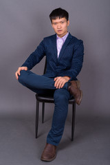 Portrait of young Chinese businessman against gray background