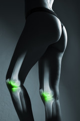 Human knee joint and leg in x-ray, on gray background. The knee joint is highlighted by green colour.