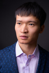 Portrait of young Chinese businessman against gray background