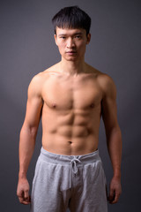 Young shirtless Chinese man against gray background