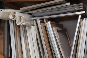 Old canvases on the stretcher, stretchers and canvases in rolls in one heap under the wall, in the...