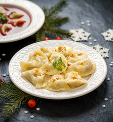 Christmas dumplings stuffed with  mushroom and cabbage on a white plate on a dark background....