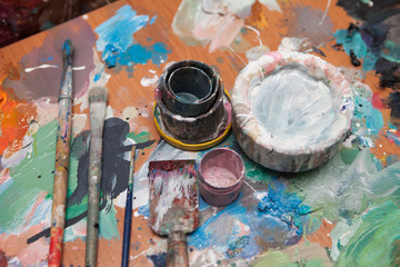 Oil paints and paint brushes on a palette, in the studio of artist.