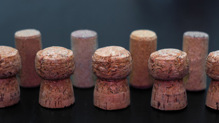 corks of champagne and wine on a black wooden surface in orderly form