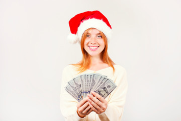 Money as a Christmas present concept. Portrait of happy young redheaded woman holding bunch of one hundred dollar bills received as new years gift. White isolated background, copy space, close up.