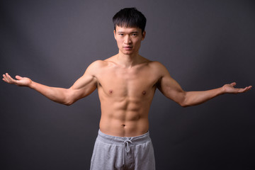 Fototapeta premium Young shirtless Chinese man against gray background