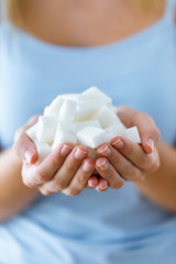 White sugar cubes in the woman hands. Heap of white sugar.