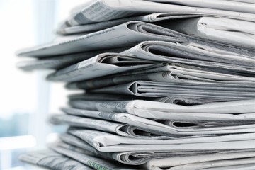 Pile of printed newspapers on white background