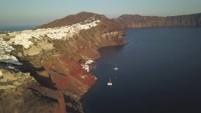 Tilt up aerial, town of Oia overlooks boats