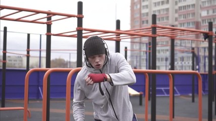 Man in a training mask on his face boxing on a sports street playground,slow mo