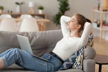 Relaxed woman sitting lying on sofa at home. Female closing eyes has a break after study or...