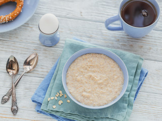 Oatmeal porridge bowl on the white wooden background.