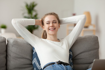 Attractive woman smiling sitting on sofa in living room alone at home has a break after fruitful...