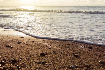 Amazing beach sunset with endless horizon and stones in the foreground.
