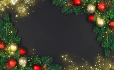 The branch of a Christmas tree with xmas decorations and magical stardust on a black background