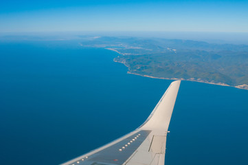 Fototapeta na wymiar Wing of airplane flying above on seacoast
