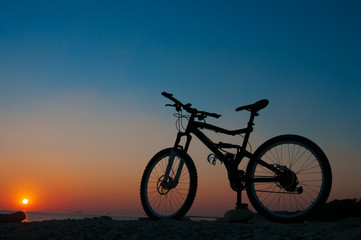 Fototapeta na wymiar Silhouette of mountain bicycle against sunset at the seacoast