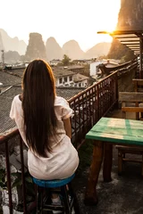 Foto op Canvas Yangshuo, China Mountainous Landscape Exotic Asian Sunset Travel.girl watching sunset on the roof of the house © ritiniya