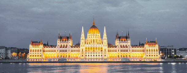Naklejka premium Parliament building in Budapest, Hungary. Building facade with reflection in water. Beautiful picture at sunset