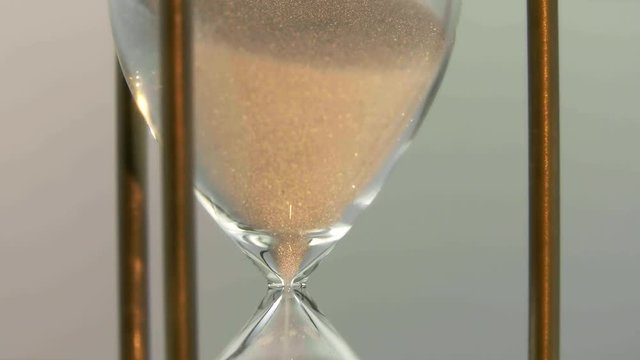 Vintage hourglass with white sand pouring