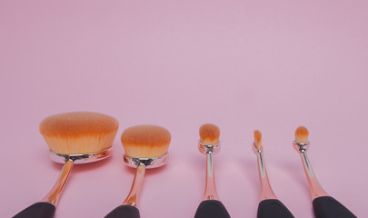 Set of oval brushes for makeup on pink background