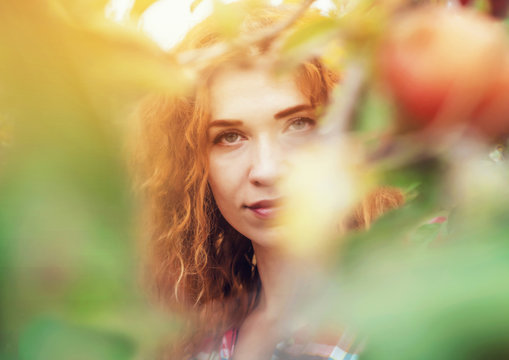 Red-haired girl portrait in the garden for the leaves and fruits of the apple tree