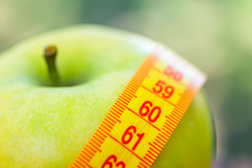 Dieting concept. Green apple with measuring tape. Green apples measured the meter, sports apple