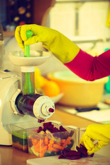 Woman make vegetables juice in juicer machine