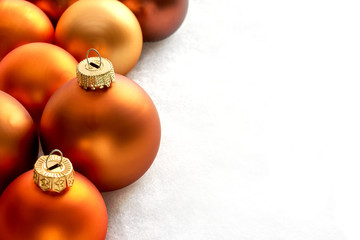 Mat bronze orange colored chtristmas balls on a white snowy background for use as a christmas card...