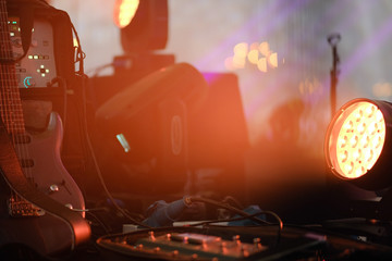 Electric guitar stands on the stage in a darkish room or studio.