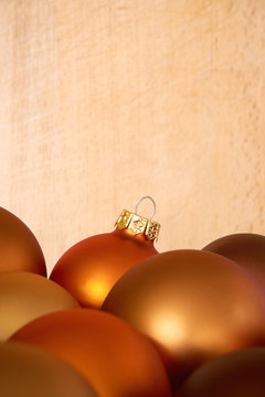 Mat bronze orange colored chtristmas balls in front of a woorden background for use as a christmas card template with copy space. Vertical image