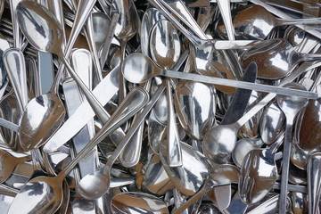 Background of old dusty, stained, shiny metal spoons and knives at a flea market