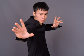 Studio shot of young Chinese man against gray background