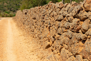 The stone wall behind the road.