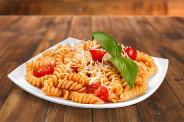 A baked dish of fusilli or pasta spirals, with cherry tomatoes - obrazy, fototapety, plakaty