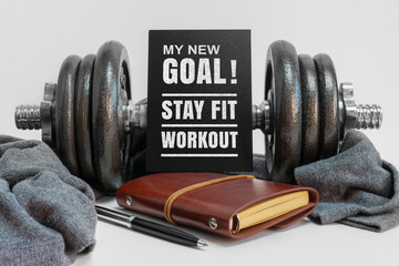 Inspirational new year concept and healthy lifestyle quote. Dumbbell and Notepad. My New Goal, Stay Fit Workout.