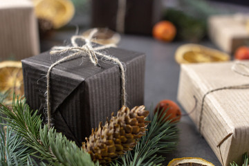 Christmas gift boxes with pine branches and dried oranges on dark texture surface.