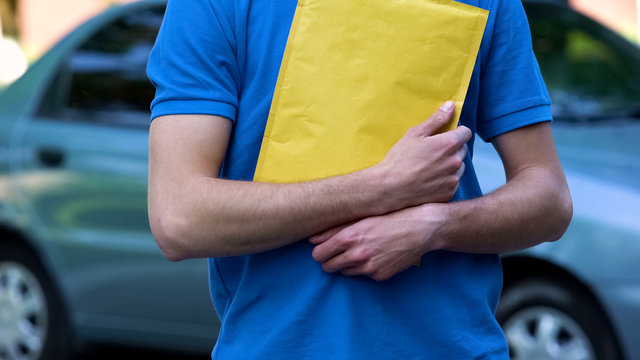 Male courier holding package with documents, protection door to door shipping