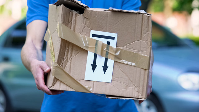 Frightened delivery worker giving broken customer parcel, shipment accident
