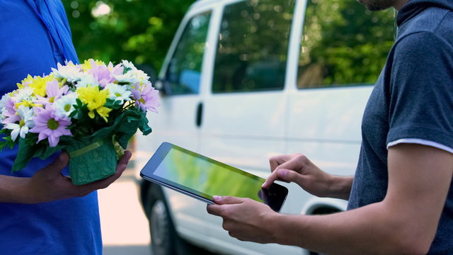 Man Appending Signature On Tablet And Receiving Flower Present From Delivery Man