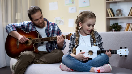 Dad with guitar and daughter with ukulele playing song, competition rehearsal