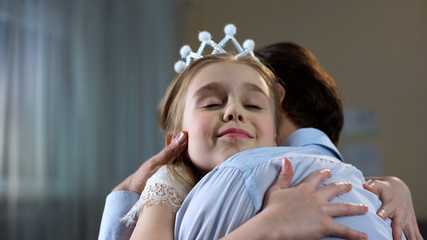 Cute female kid in princess crown hugging father, tender relations, holidays © motortion