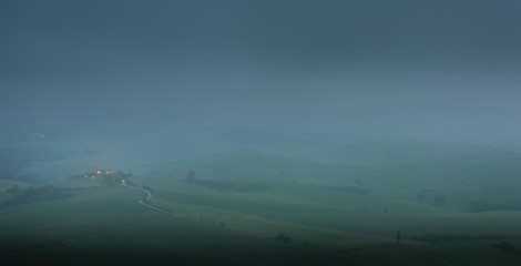 Tuscany, Crete Senesi rural sunset landscape. Countryside farm, cypresses trees, green field, sun light and cloud. Italy, Europe.