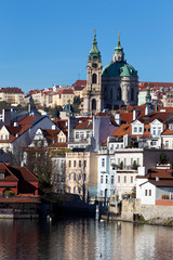 Fototapeta premium Colorful autumn Prague St. Nicholas' Cathedral with the Lesser Town above River Vltava in the sunny Day, Czech Republic